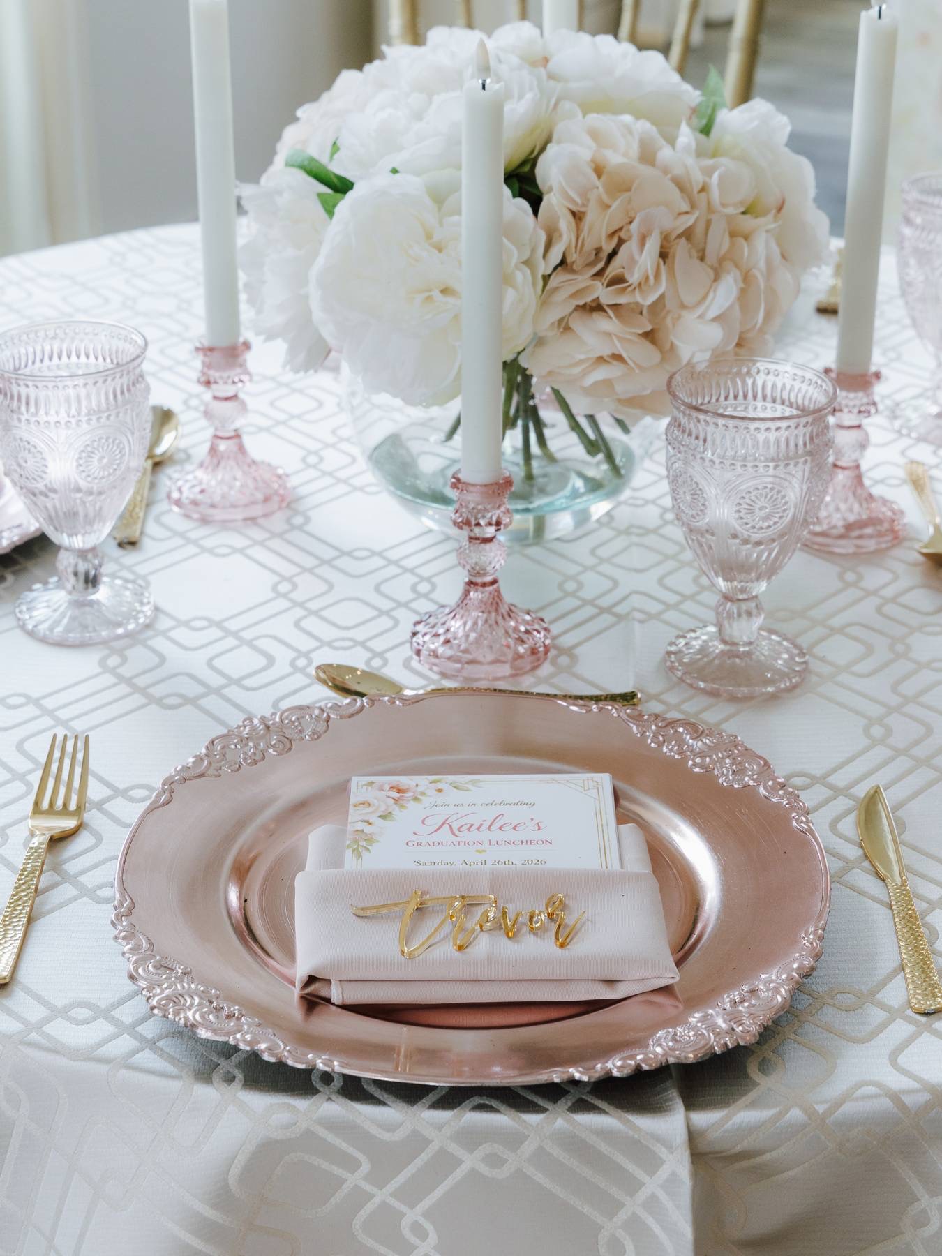 Blush charger plates, pink depression glass, and gold flatware with a peony centerpiece