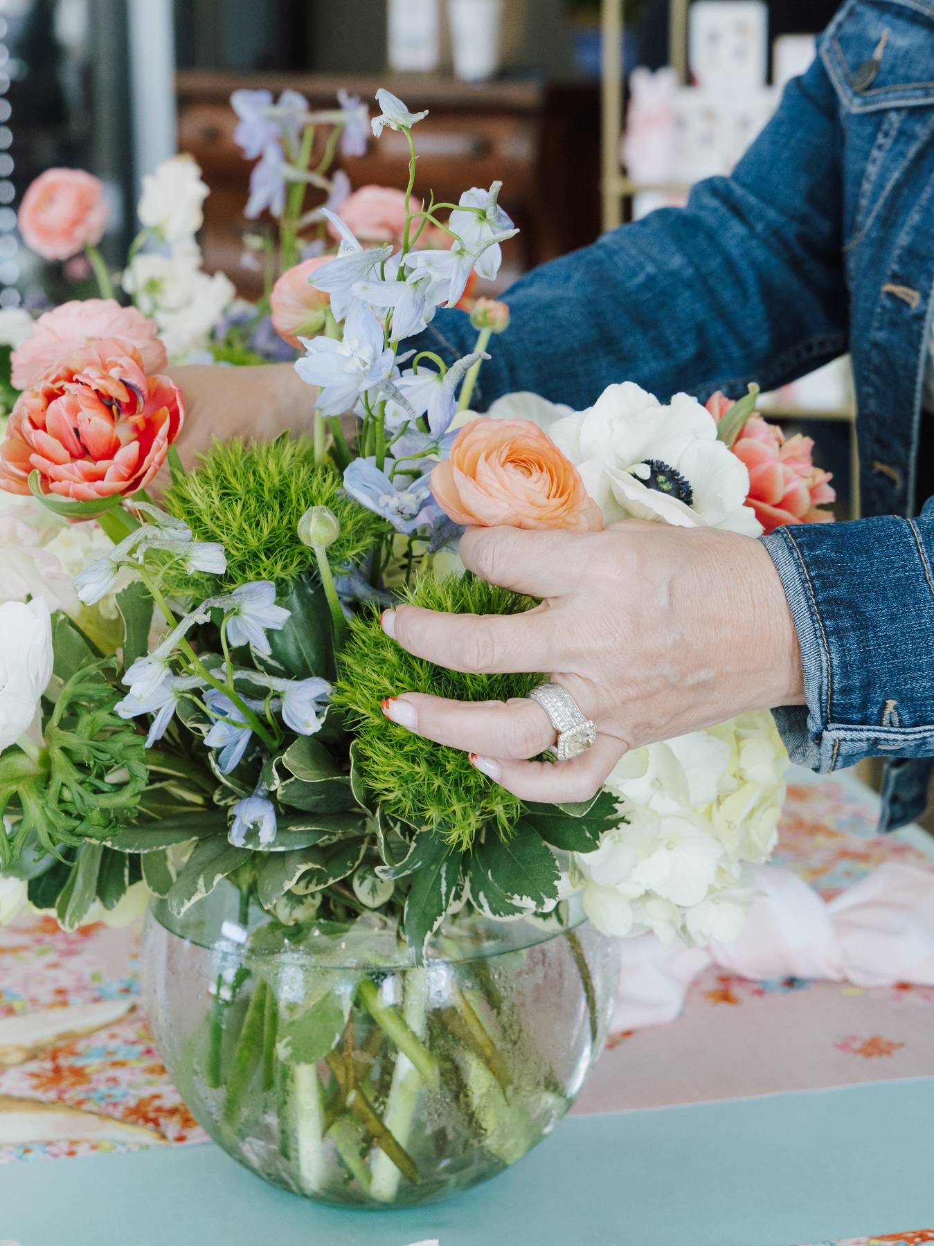 Hands tucking green dianthus into a spring floral centerpiece during a floral design class