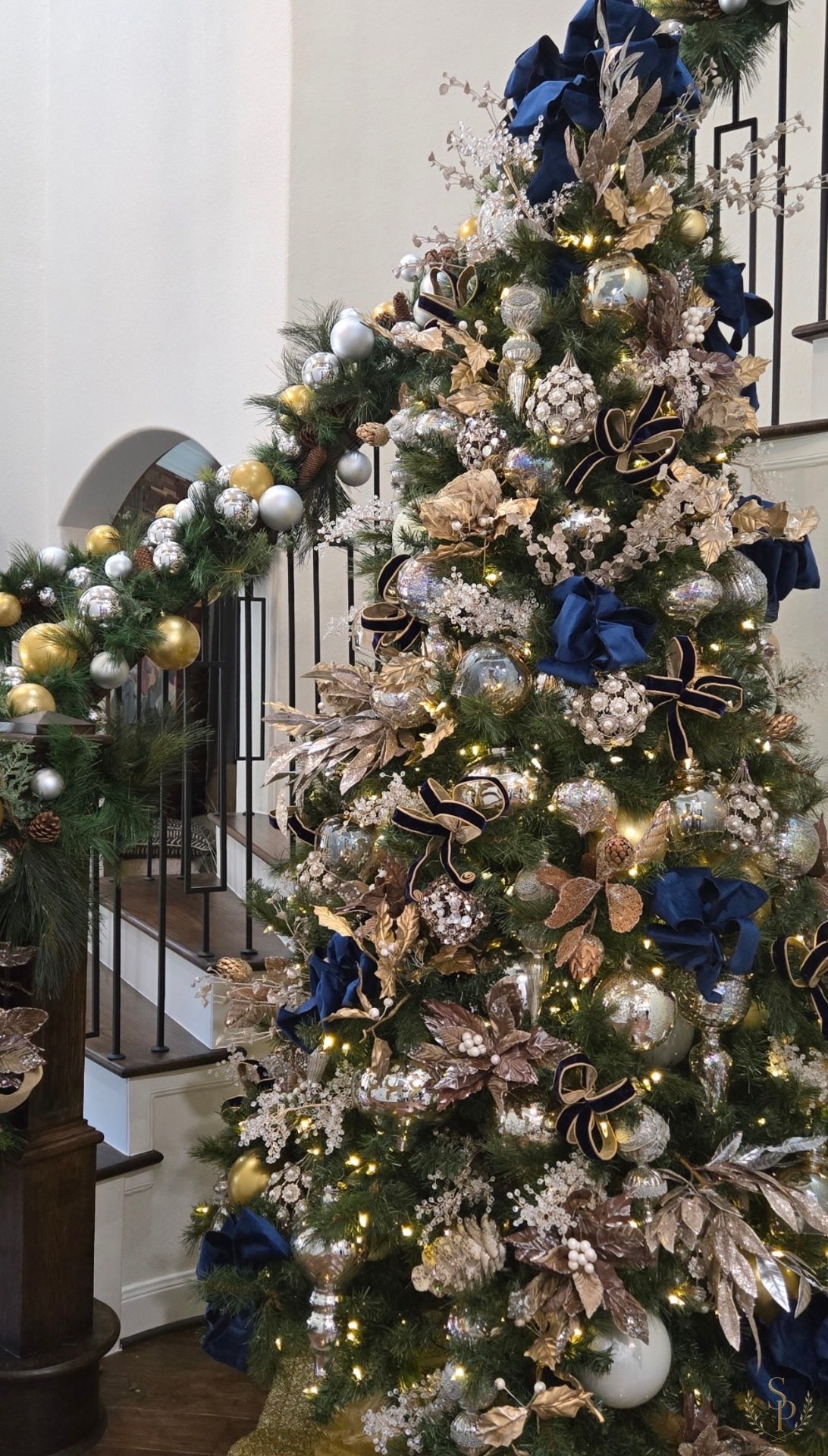 Grand staircase Christmas tree and garland styled in navy velvet, champagne, and pearl