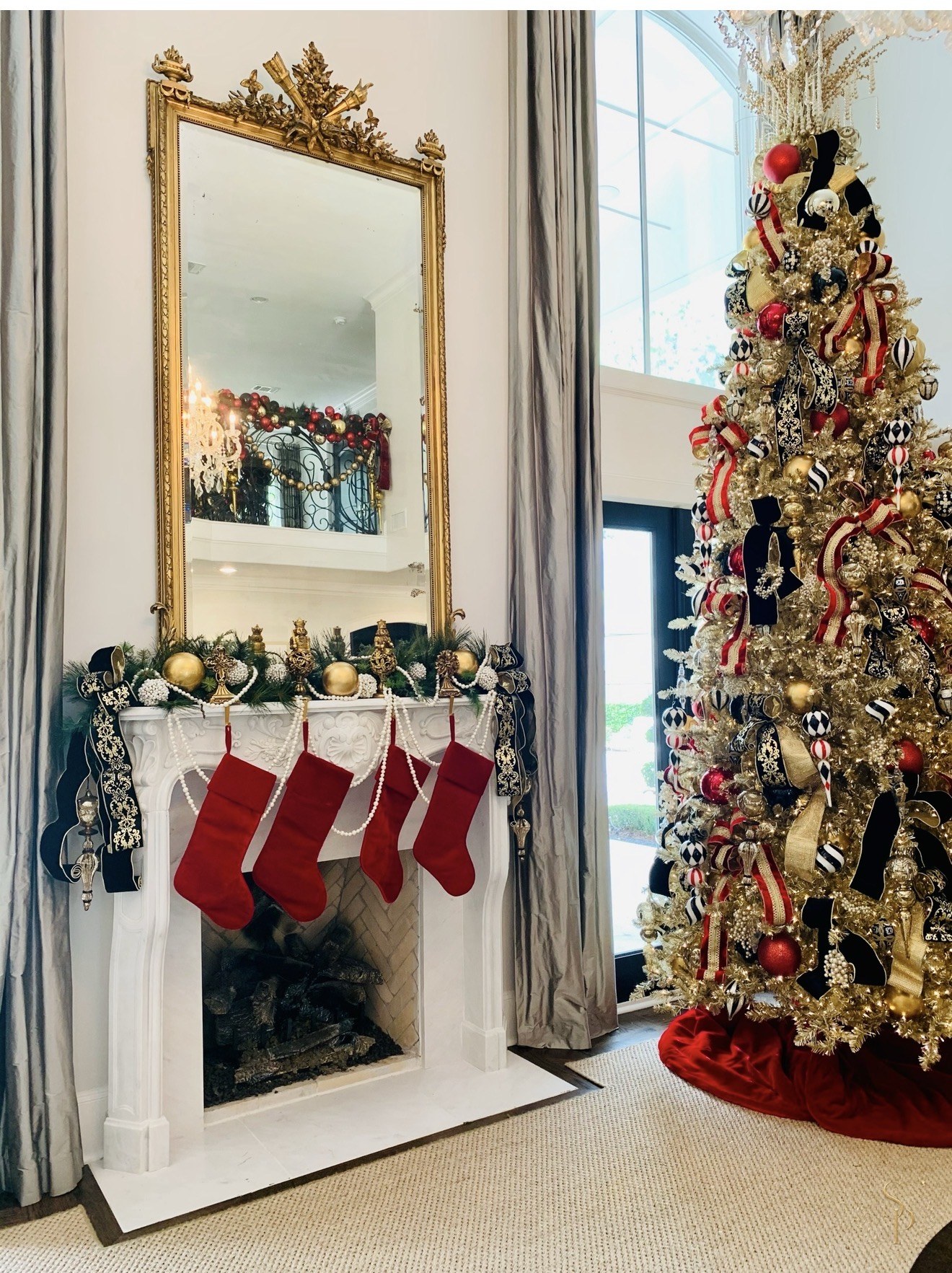 Gold Christmas tree beside a mantel styled with stockings, ribbon, and pearl garland