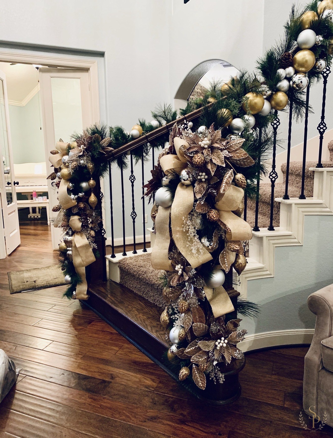 Staircase garland dressed with champagne ribbon, metallic ornaments, and florals