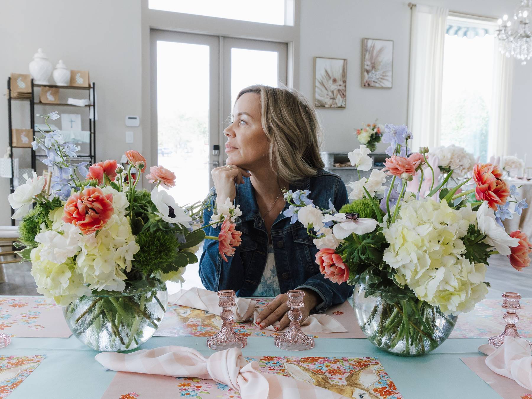 Instructor admiring paired spring centerpieces between candlesticks during a tablescape workshop