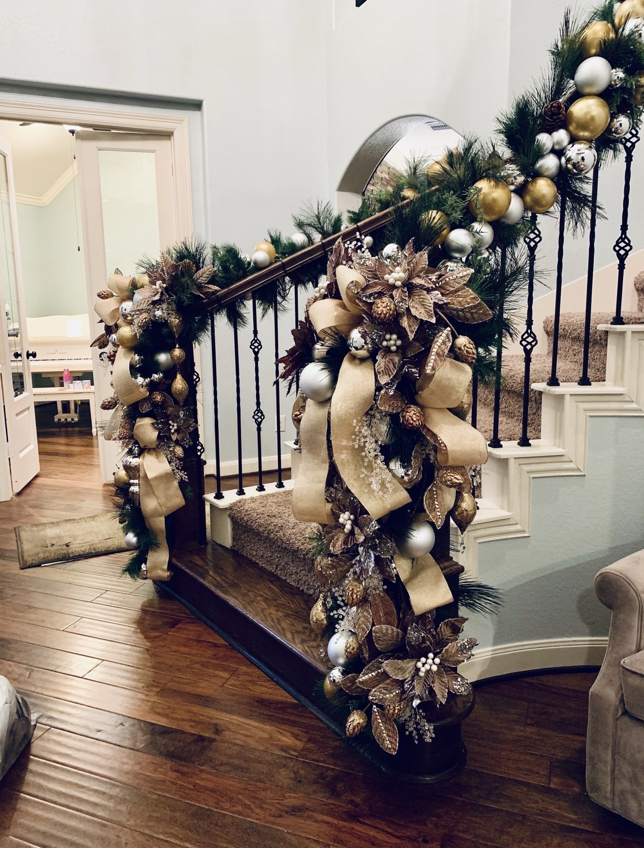 Staircase garland dressed with champagne ribbon, metallic ornaments, and florals