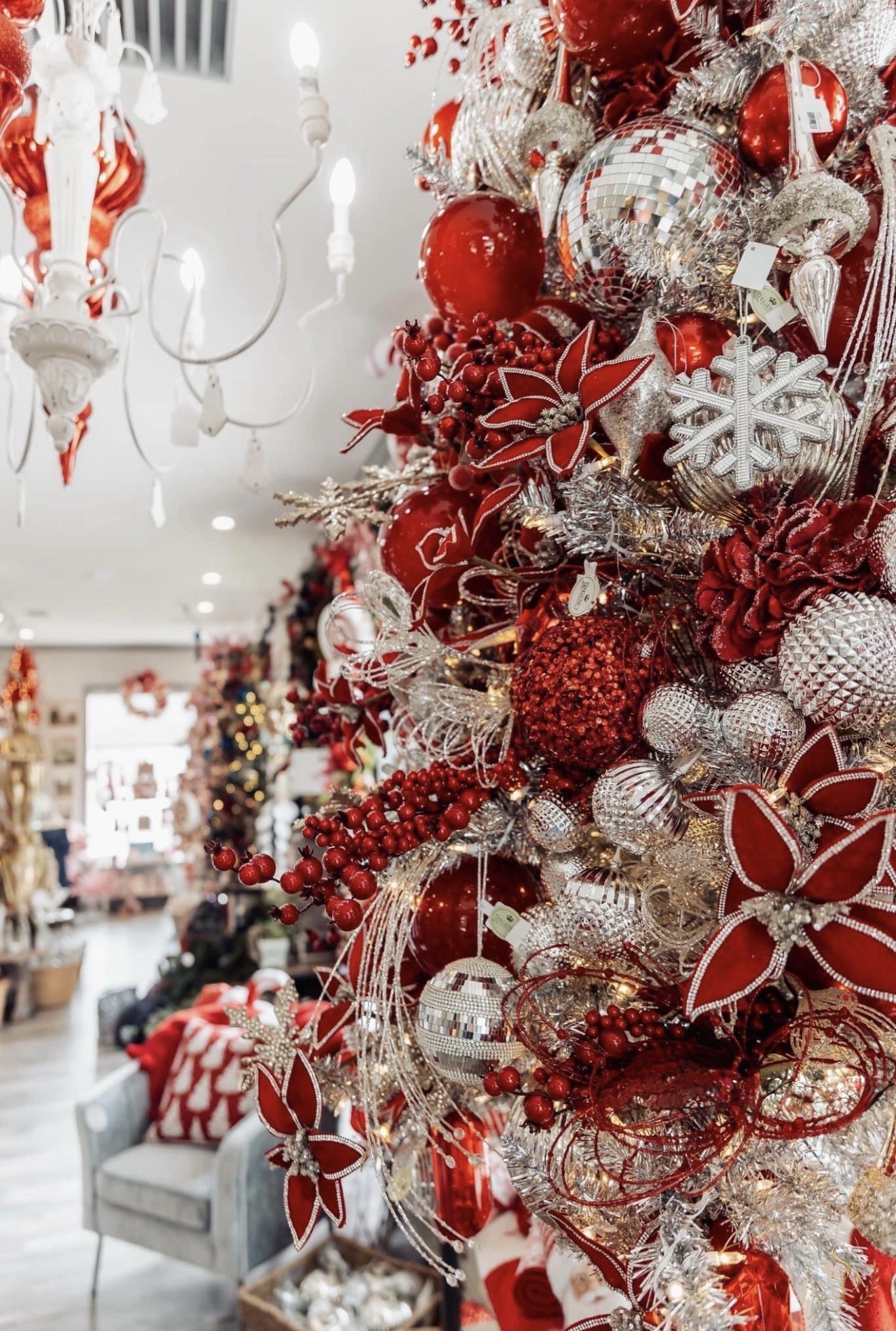 Close-up of a red and silver Christmas tree layered with poinsettias and berries