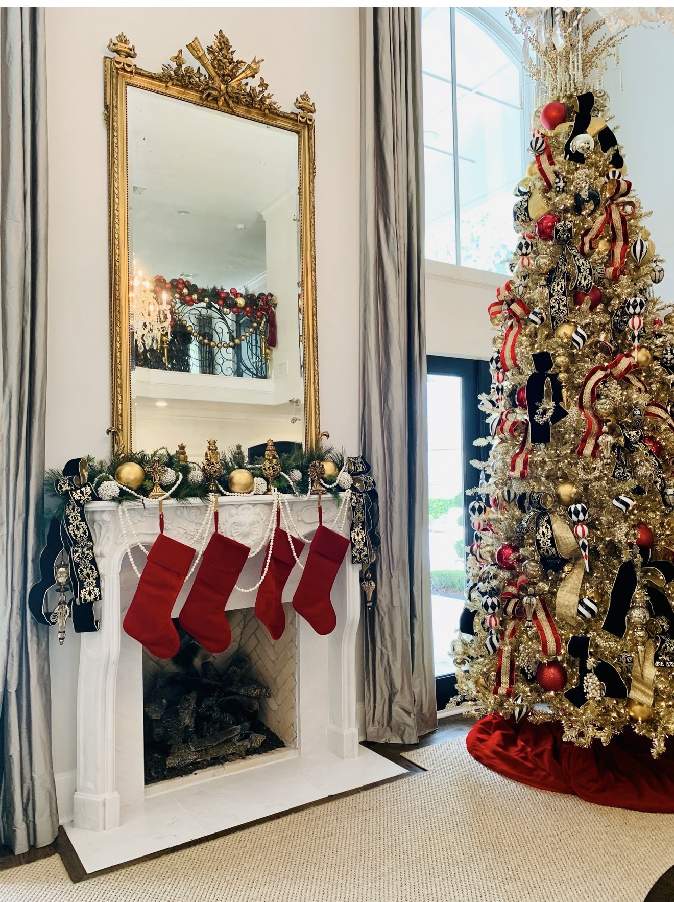 Gold Christmas tree beside a mantel styled with stockings, ribbon, and pearl garland