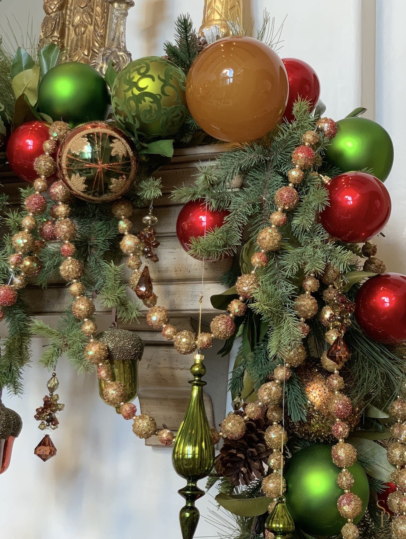 Close-up of holiday mantel garland with oversized ornaments and sparkling bead strands