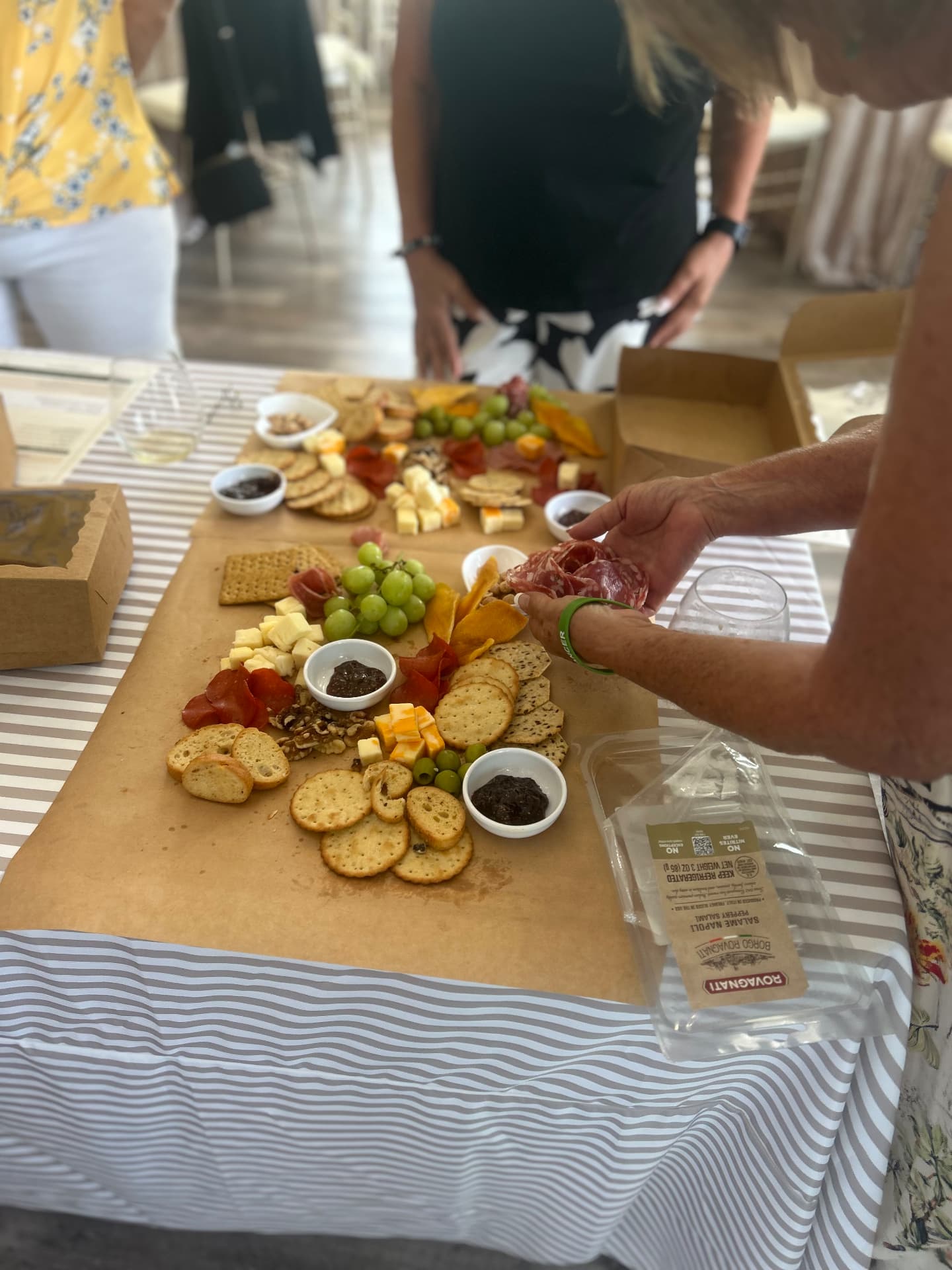 Guests adding peppered salami to a charcuterie spread during class