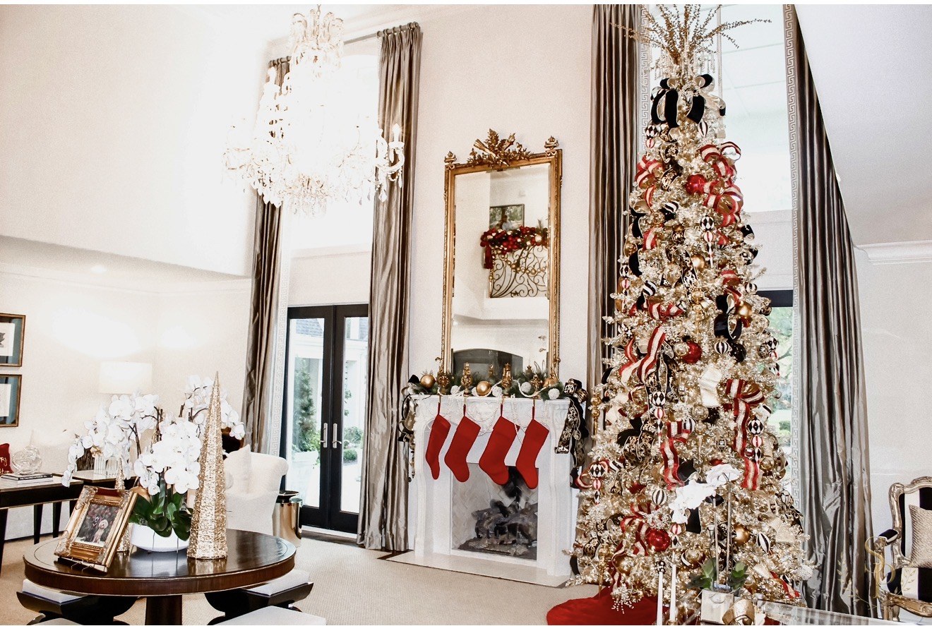 Formal room with a gilded Christmas tree, red stockings, and tall drapery