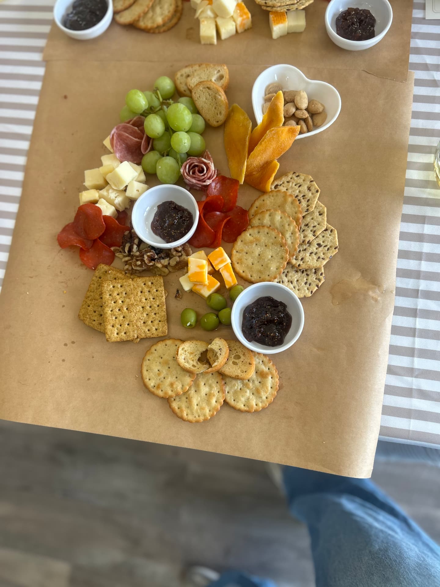Workshop grazing board styled on butcher paper with olives, manchego, and heart-shaped bowls