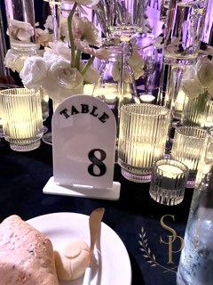 Ribbed glass votives surrounding a black-and-white Table 8 marker